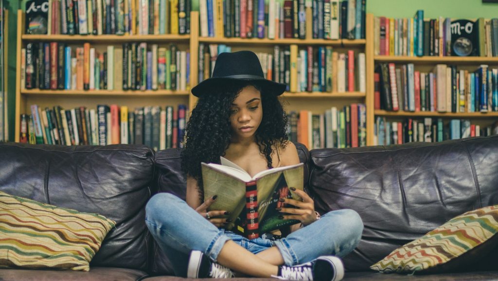 woman reading a book while sitting on black leather 3-seat couch